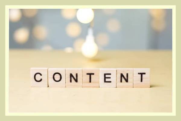 Wooden blocks spell out the word CONTENT against a blurred background with lights.