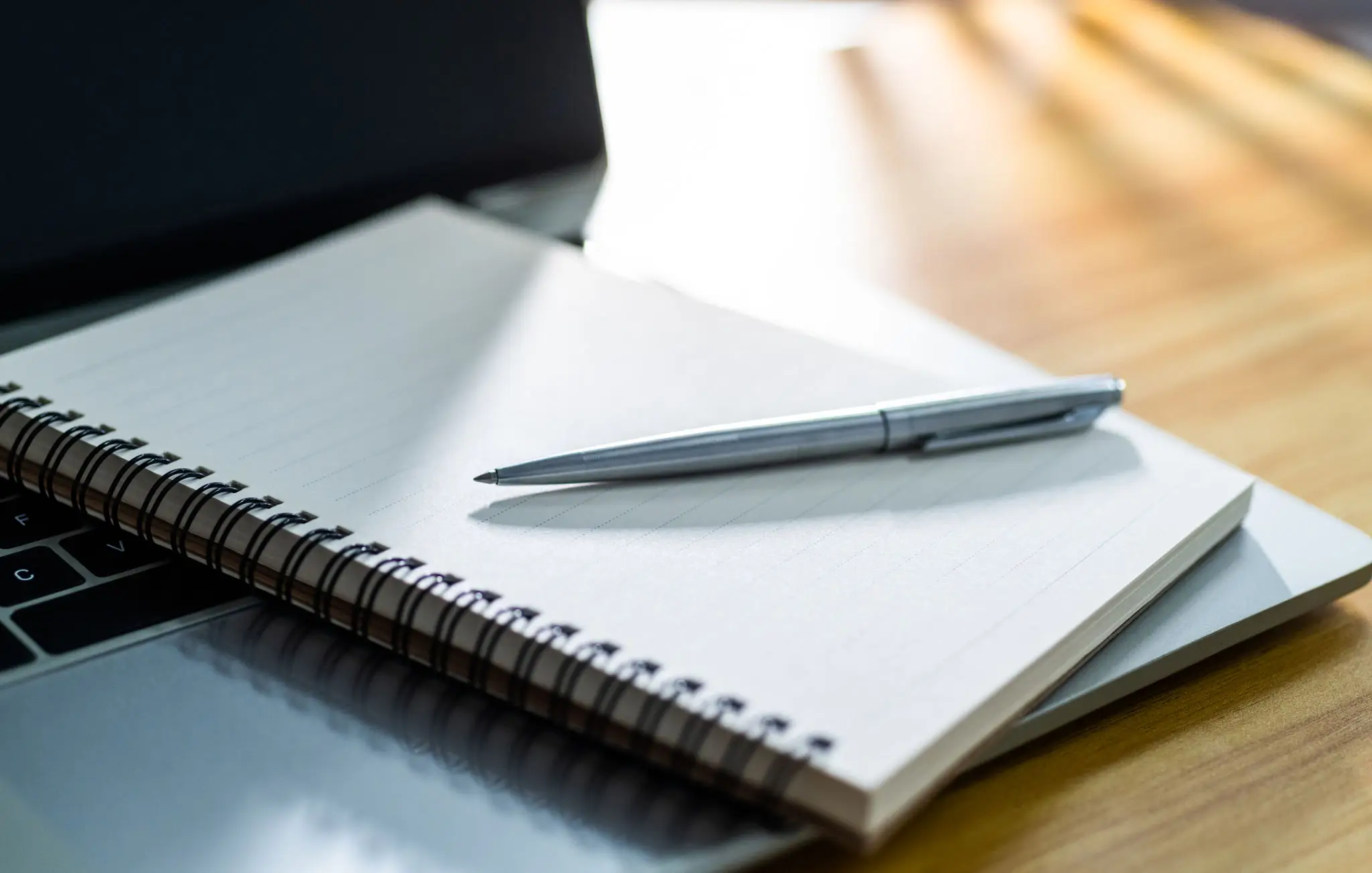 A silver pen resting on an open spiral notebook.