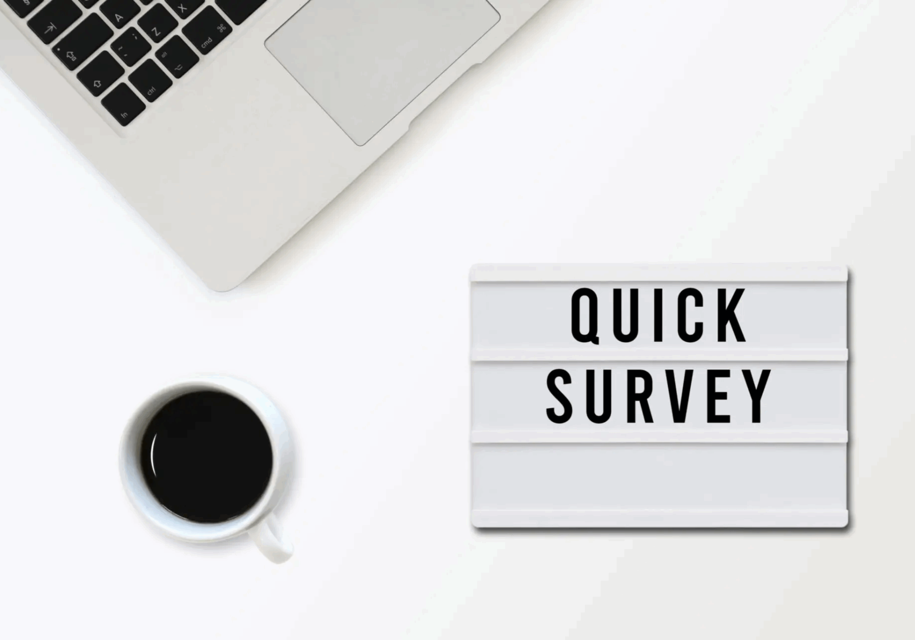 Workspace with coffee and a sign saying 'Quick Survey'.